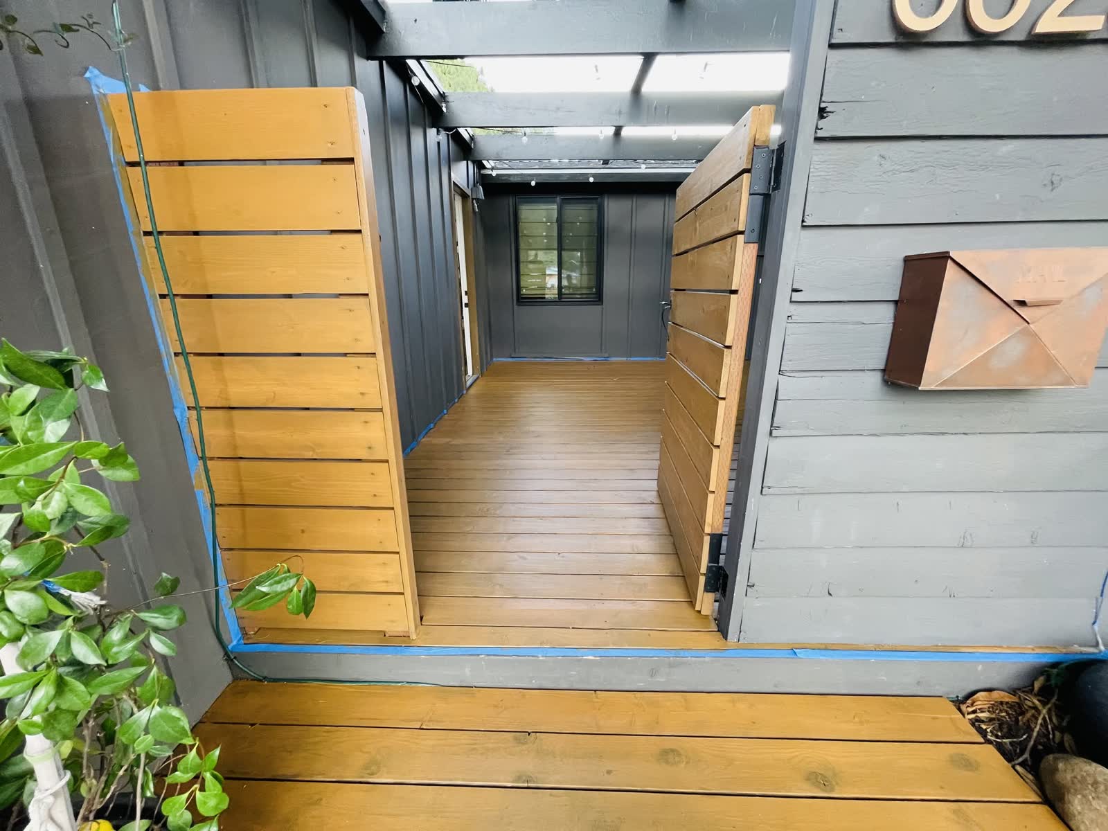 Cedar slat gates opening onto a new wood deck walkway at a dark modern home